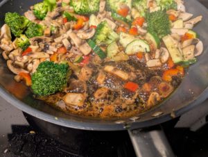 Close-up of dark balsamic reduction bubbling in the pan next to the vegetables
