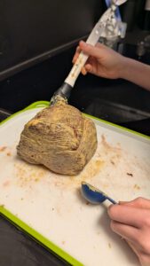 A hand brushing the seared fillet with mustard on a green-rimmed board