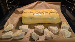 Beef Wellington on a paper-lined baking tray, ready to bake, with pastry offcut spirals beside it