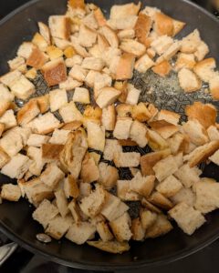 Golden bread cubes toasting in a pan