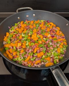 Diced pancetta, red onion, carrot and celery cooking in a wide pan for the soffritto