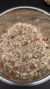 Dry mix of oat flakes, sunflower seeds, flaxseed and whole nuts in a stainless steel bowl, before the liquid is added